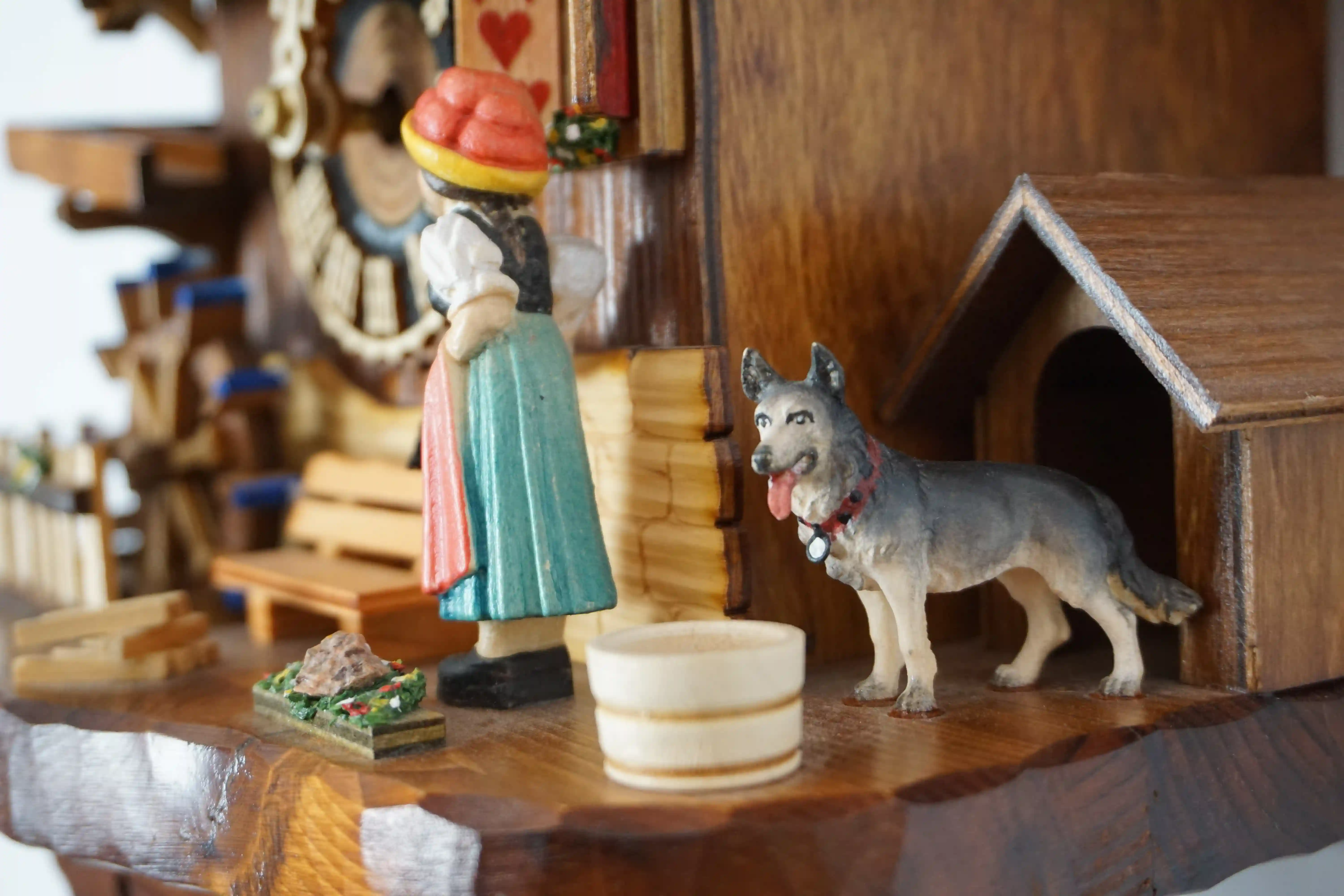 Chalet style authentic mechanical black forest cuckoo clock with shingle roof, church tower bell and black forest lady wearing traditional clothing, the lady rings the bell together with the cuckoo sound, music plays dancers dance and water wheel turns
