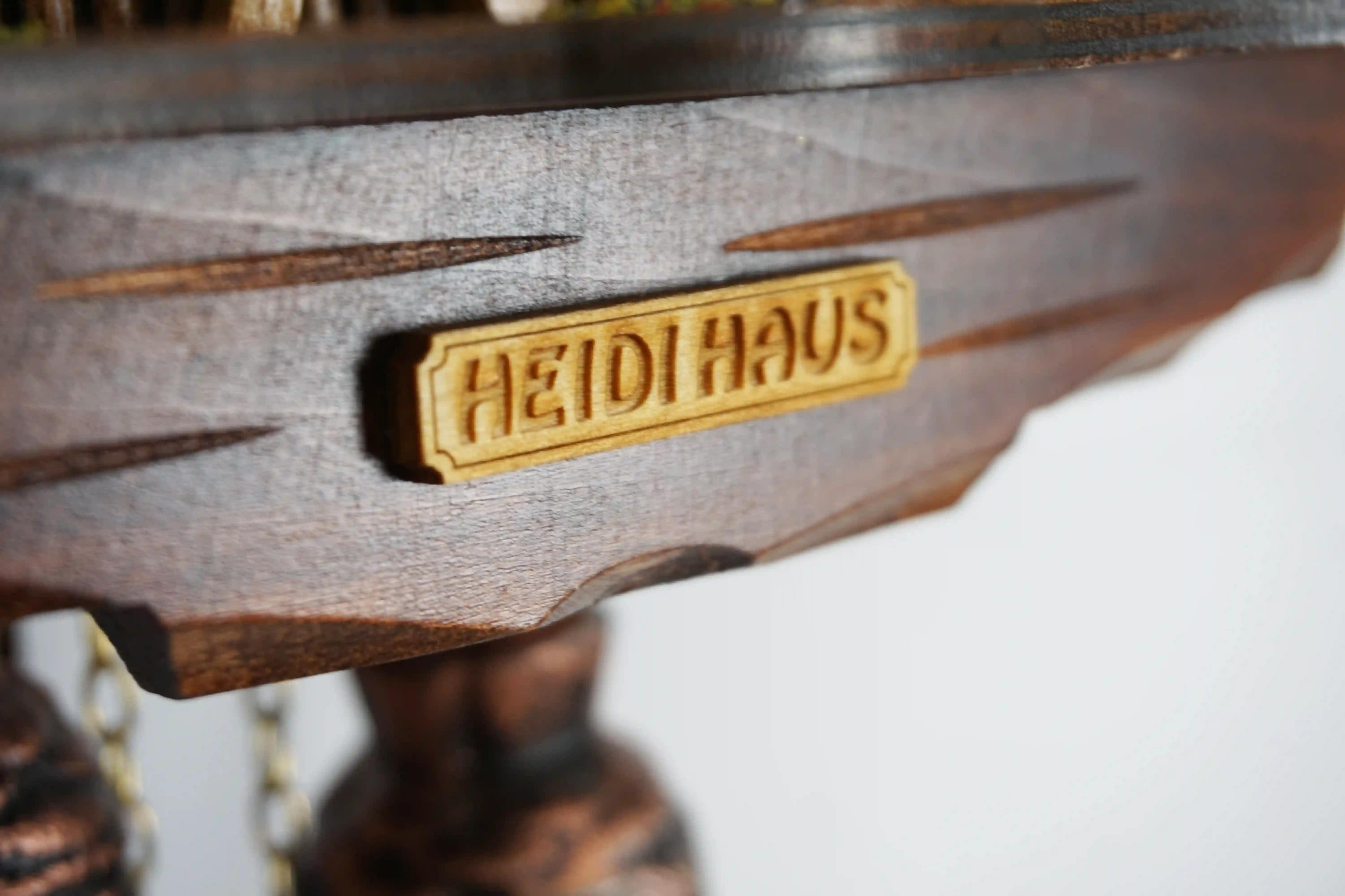 8 day mechanical black forest cuckoo clock in brown color with colorful figures from Heidi storyline, Heidi, grandpa and Peter are standing in front of the clock named Heidi House. Made by Hönes